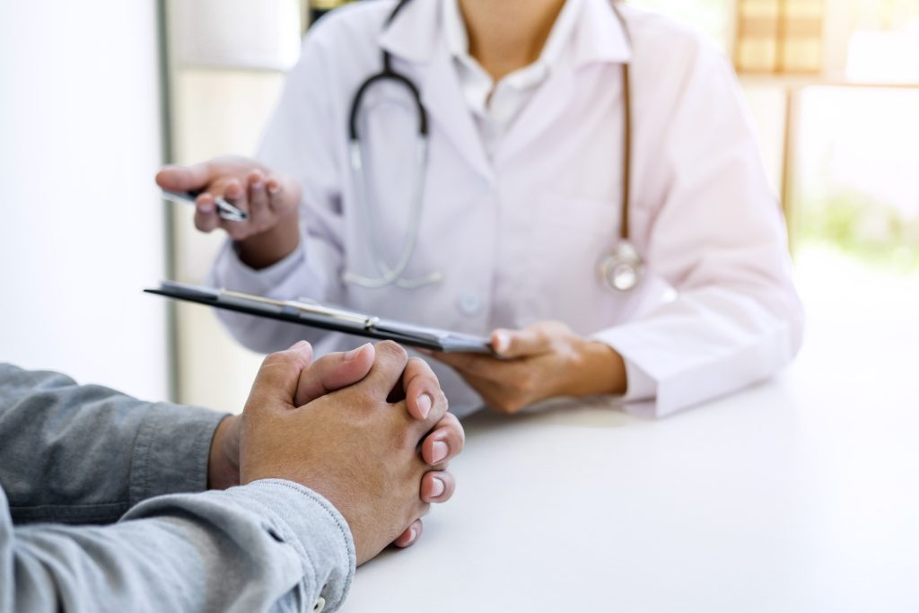 Doctor filling up an history form while consulting to patient and recommend treatment methods and how to rehabilitate