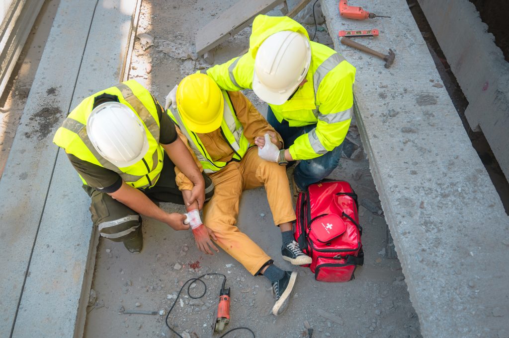 Construction worker has an accident at a construction site. Emergency help engineers provide first aid to construction workers in accidents. Safety team help a construction worker who has an accident.