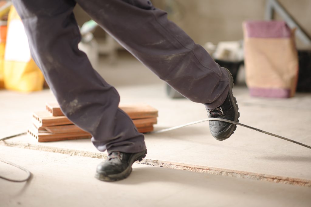 Construction worker stumbling with a cord