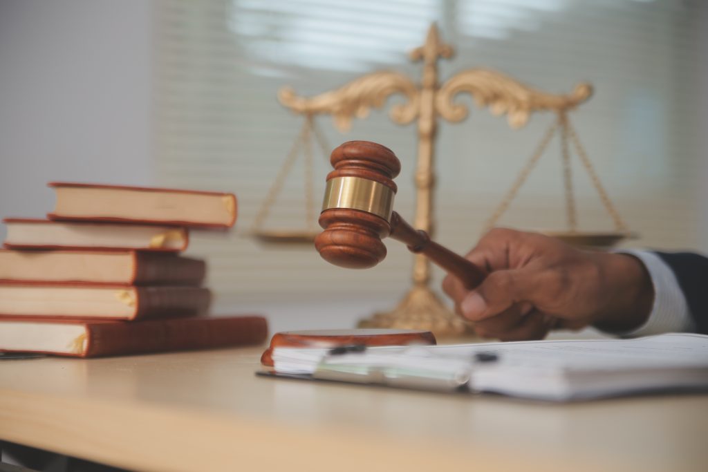 Judge gavel and miniature car symbolize auction or court case against driver who has accident and receiving vehicle insurance payment be on table in front of hands of lawyers. Selective focus