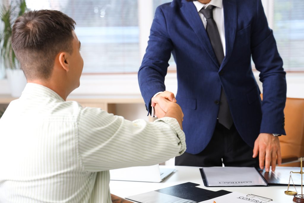Male lawyer shaking hands with client in wheelchair at office, closeup
