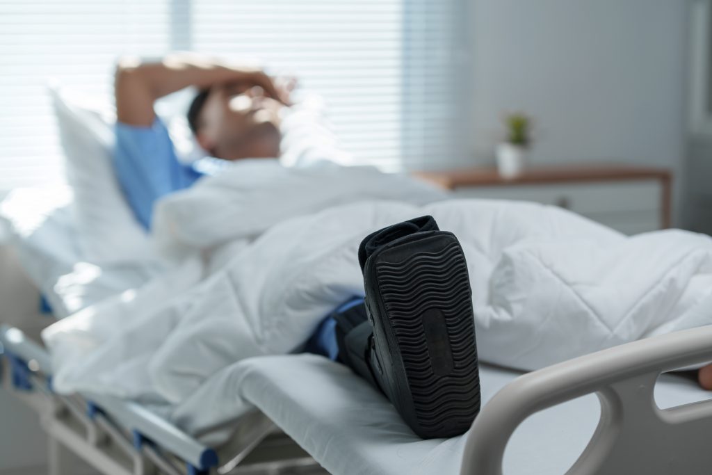 Patient recovering in hospital bed with walking boot: dealing with foot or ankle injury