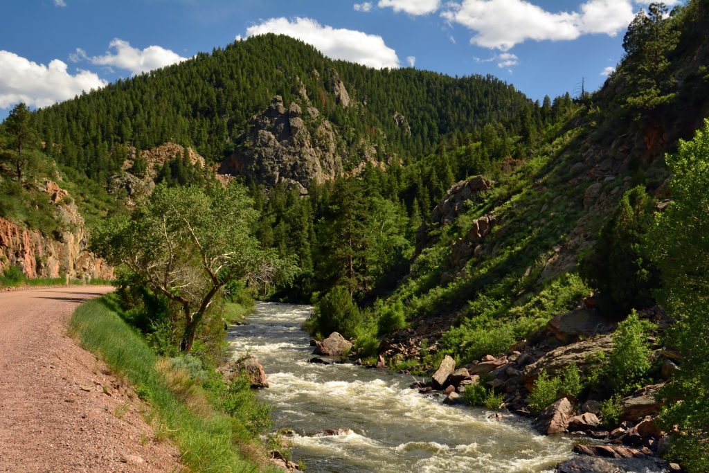 cycling trail, granite peaks and rapids on in the south platte river on a sunny summer day in waterton canyon, littleton, colorado